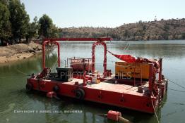 Image du Maroc Professionnelle de  Plusieurs machines sont installées au milieu du barrage pour le nettoyage du fond (retrait des sédiments qui s'y accumulent), le Barrage Machraa Hamadi dont la capacité est de 42 Millions de m3, est construit sur l'Oued Moulouya, il permet, depuis 1956, d'approvisionner la région et d'irriguer les terres de cultures, ce barrage fournit en eau potable les ville de Nador, Oujda, il permet également l'approvisionnement des centre de Taourirte et El Aïoun Sidi Mellouk. Samedi 1er octobre 2005. (Photo / Abdeljalil Bounhar) 